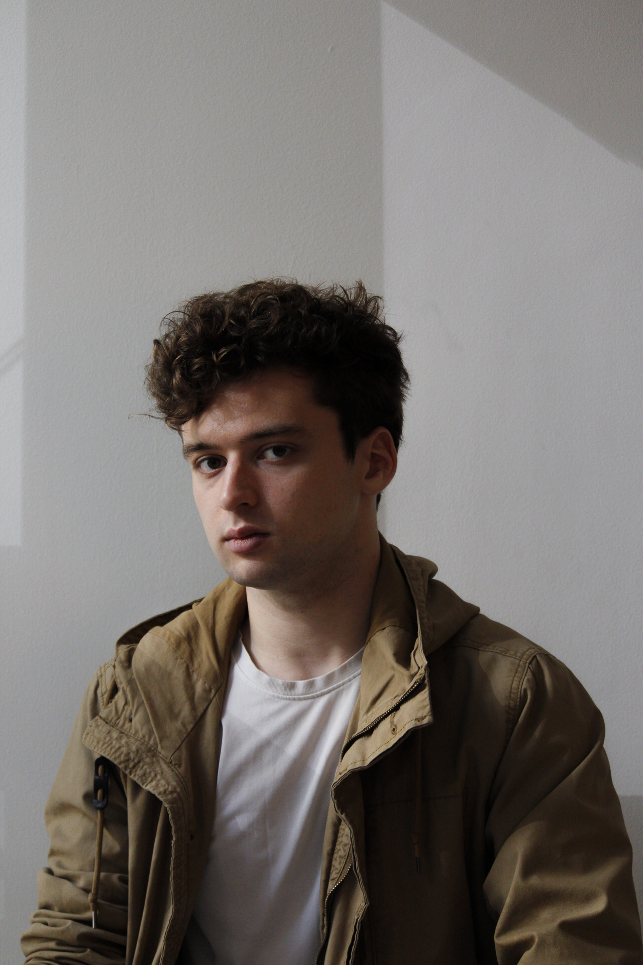 Portrait of the photographer in a tan jacket against a pale wall